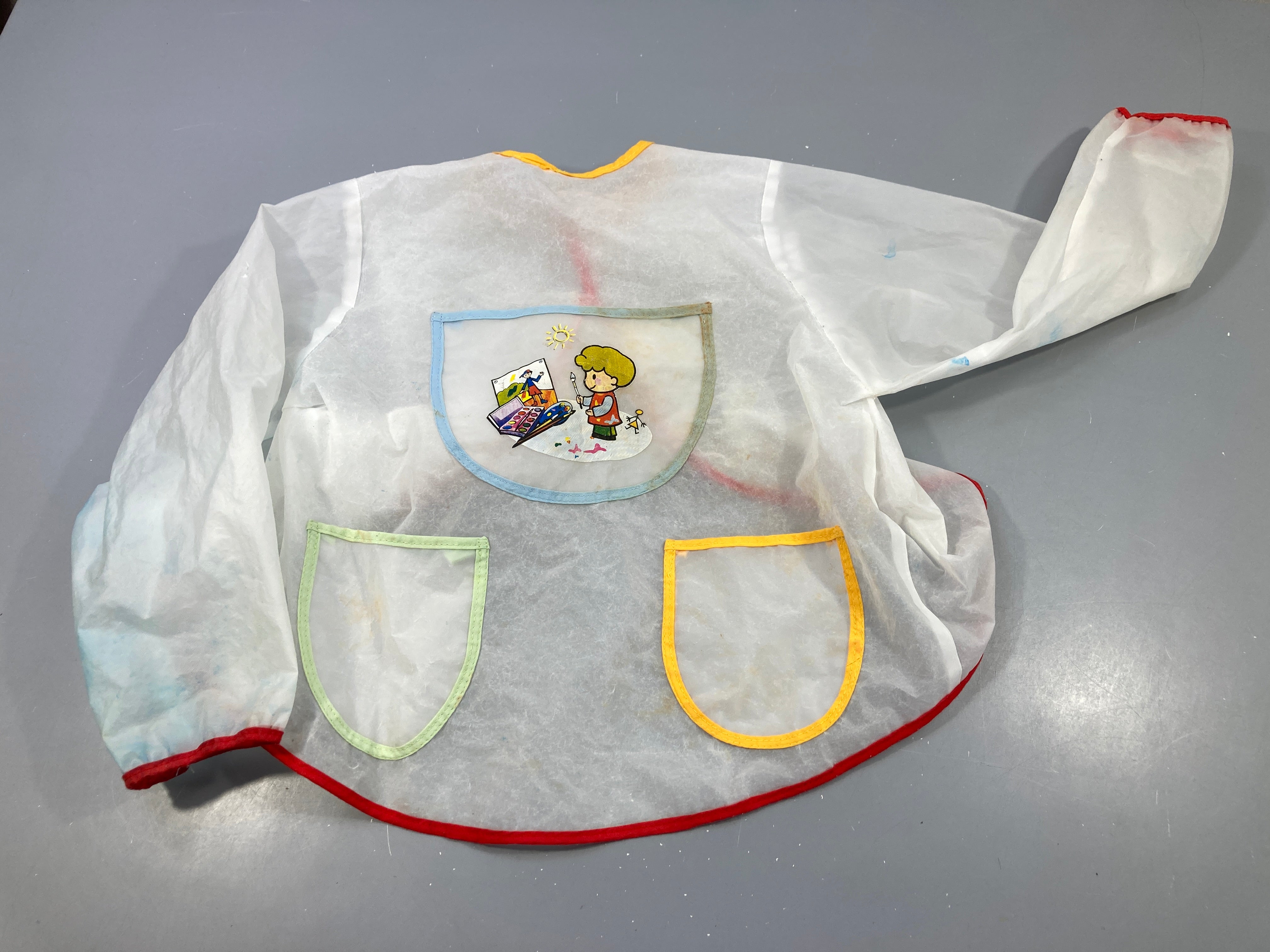 Tablier en plastique , petit garçon qui peint, plusieurs traces de peinture