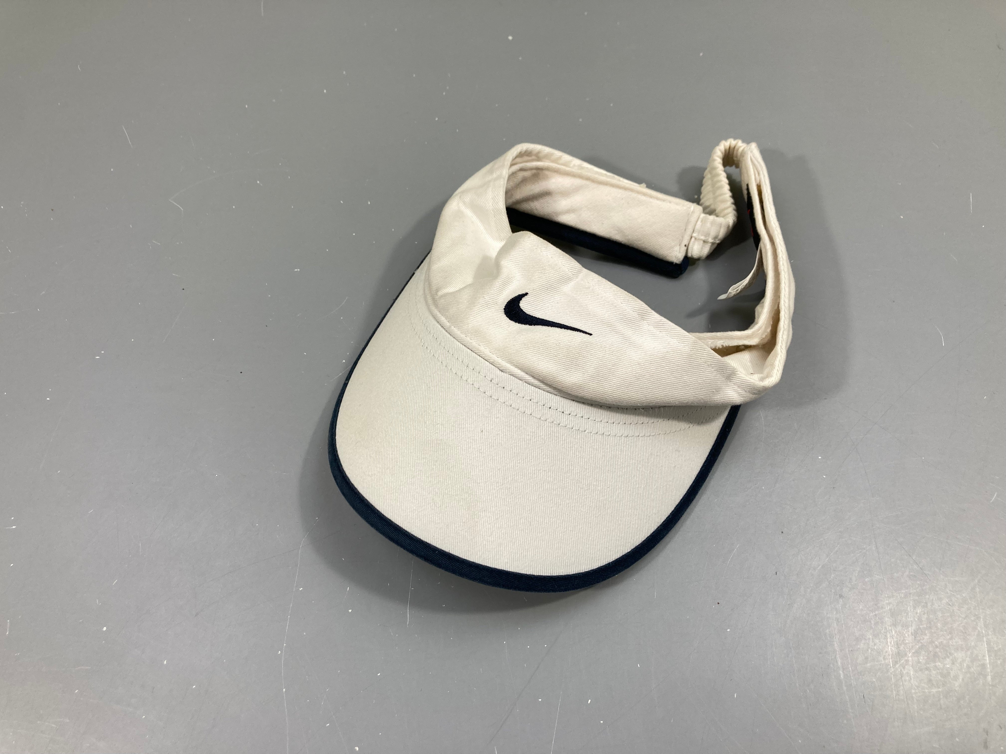 Casquette visière blanc-bleu Nike Très légèrement gondolé sur un endroit à rafraichir