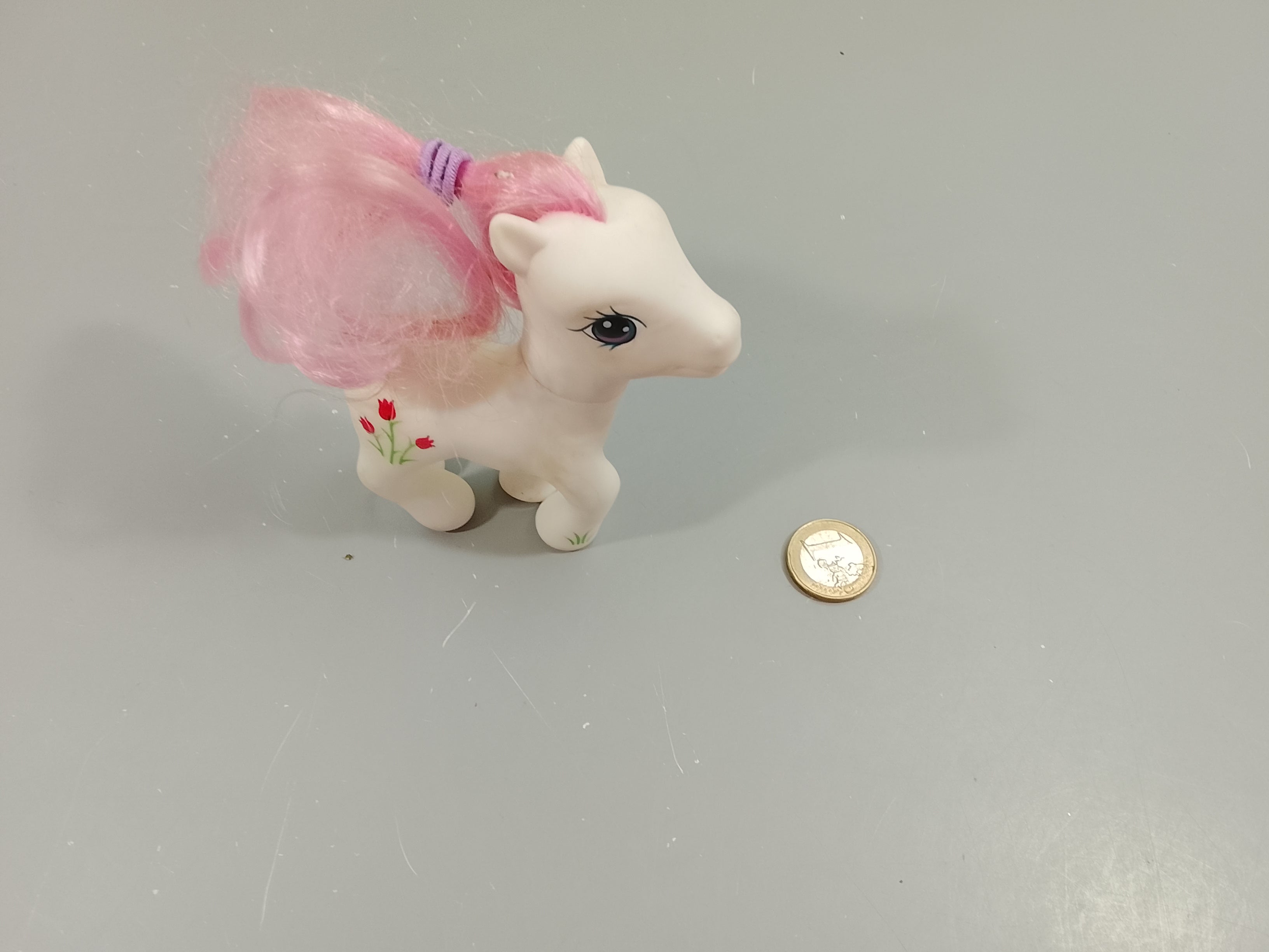 Bébé poney blanc ,petites fleurs rouges