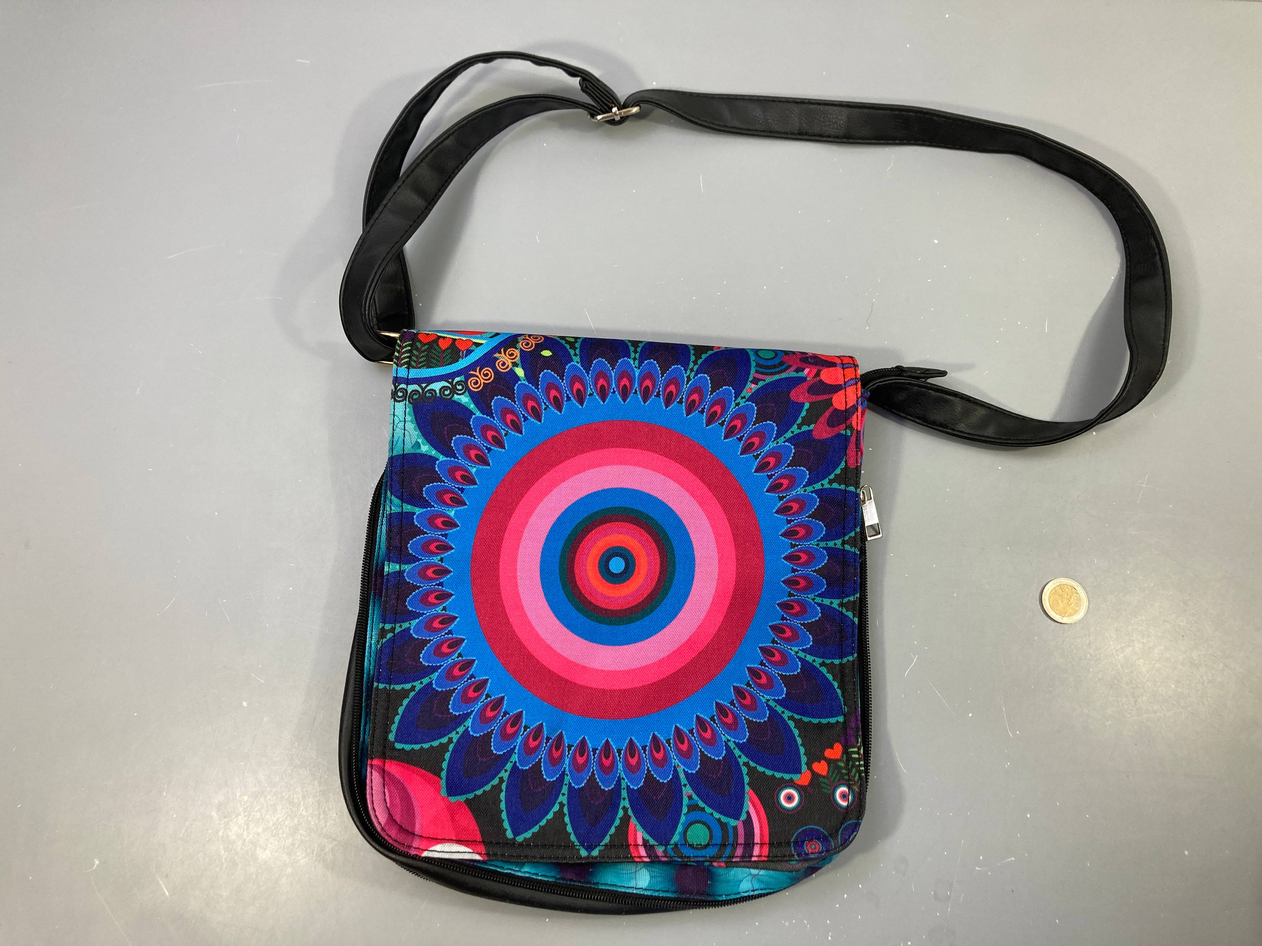 Sac à bandoulière Desigual motif coloré Mandala extensible grâce à une fermeture éclair qui fait le tour du sac pour augmenter sa capacité.