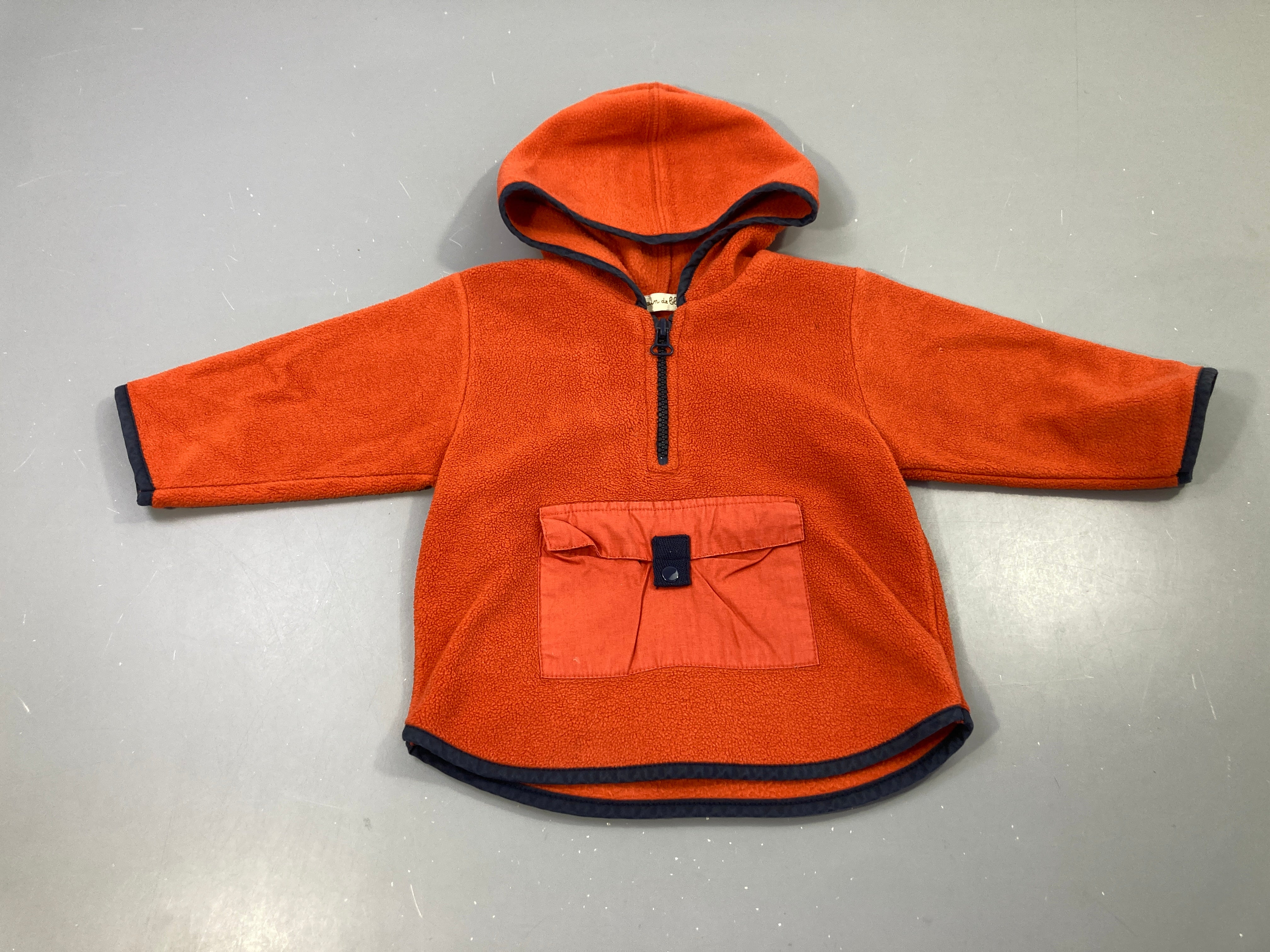 Polar à capuche orange bord bleu poche.