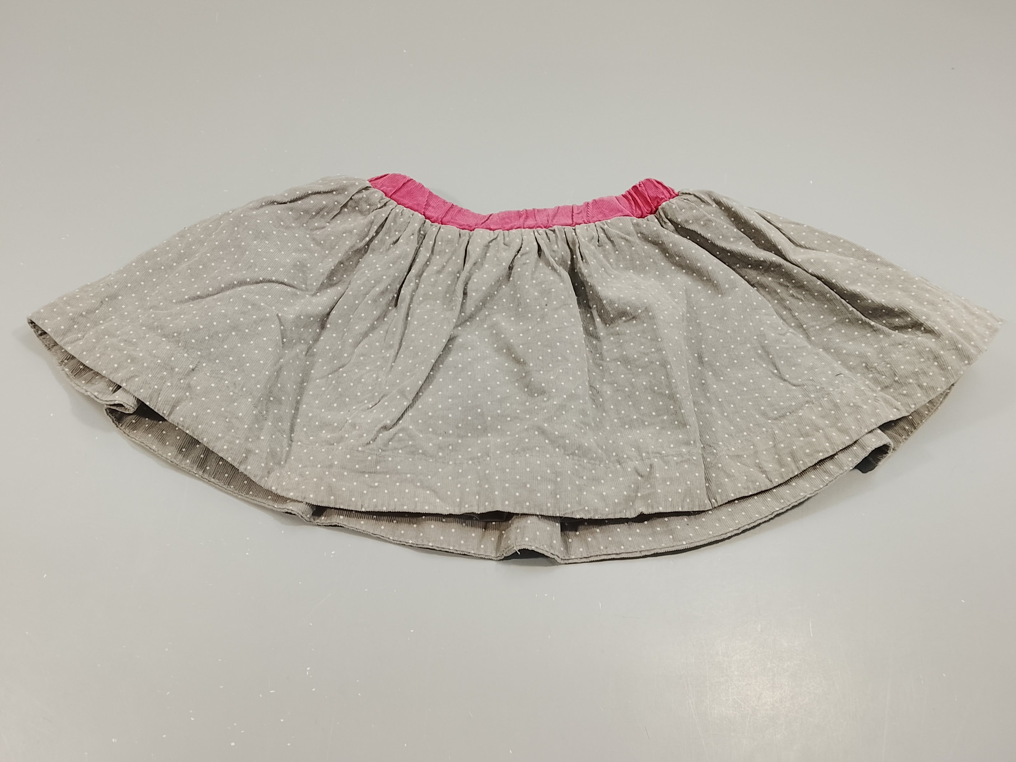 Jupe en velours côtelé gris à pois blancs, taille rose. Doublé jersey