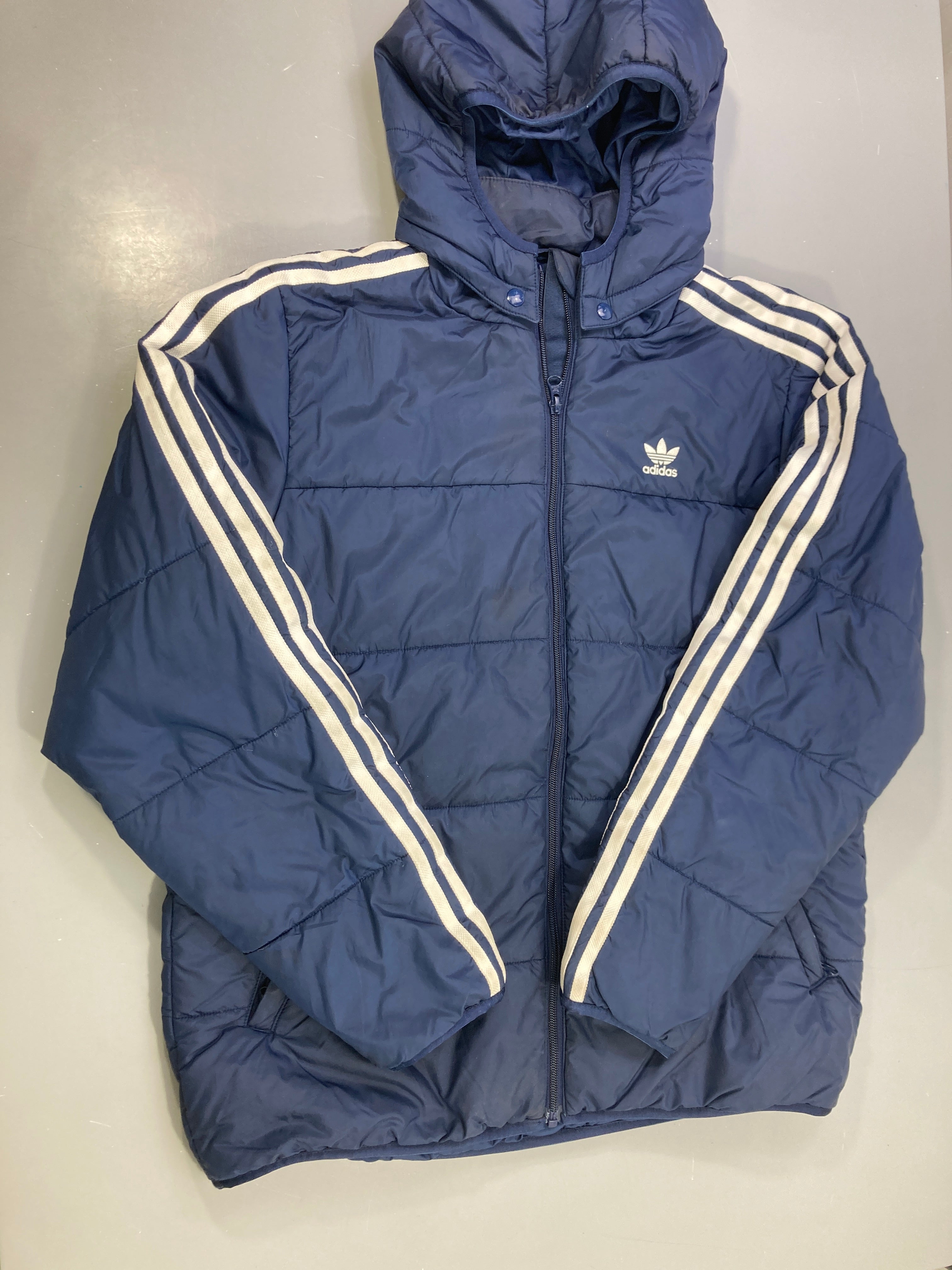 Attention - Défaut! Doudoune bleu marine bandes blanches zippée capuche, bas de la manche se découd et liseret manches tachés