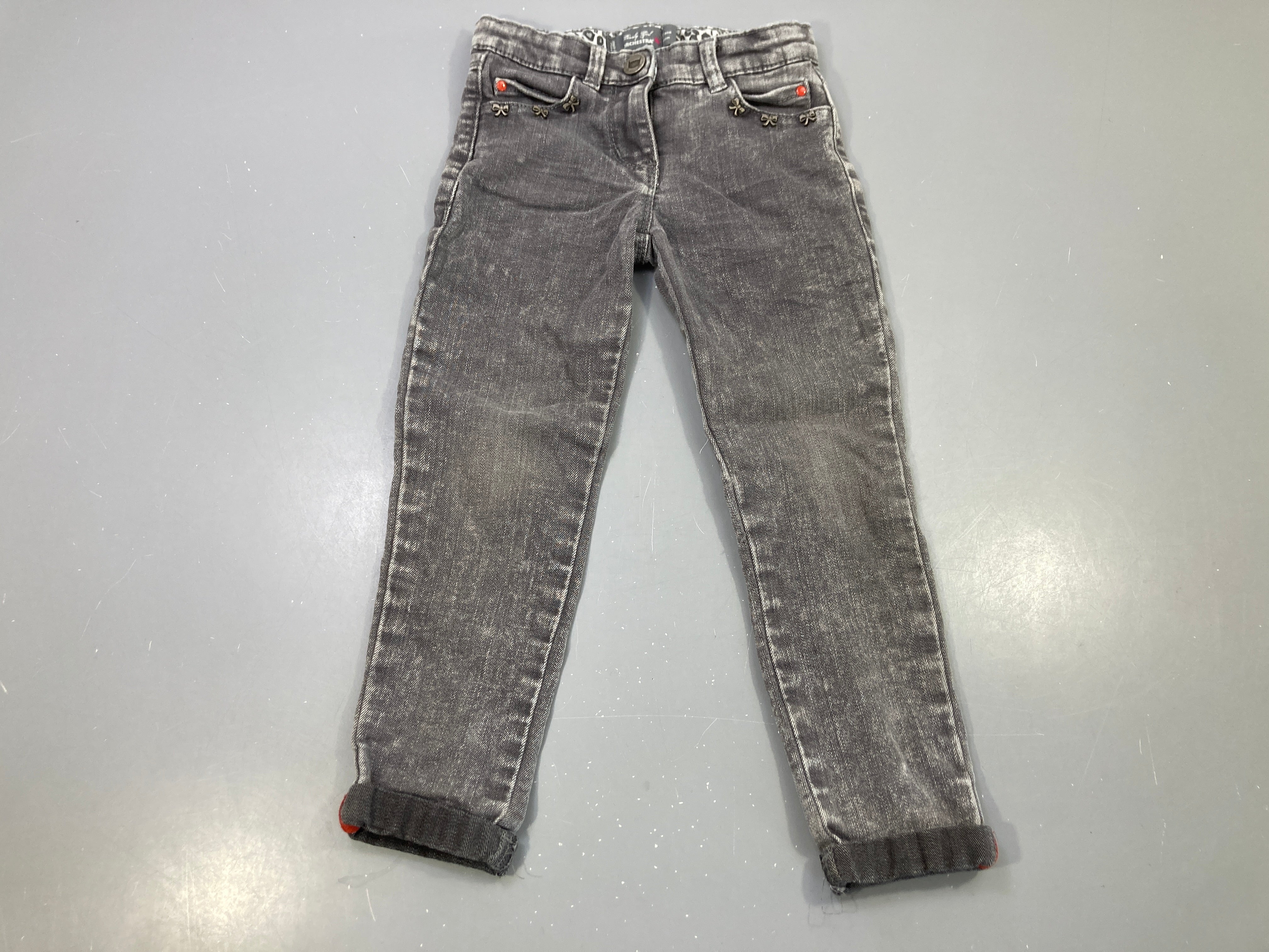 Pantalon jean gris délavé, noeuds métalliques, revers