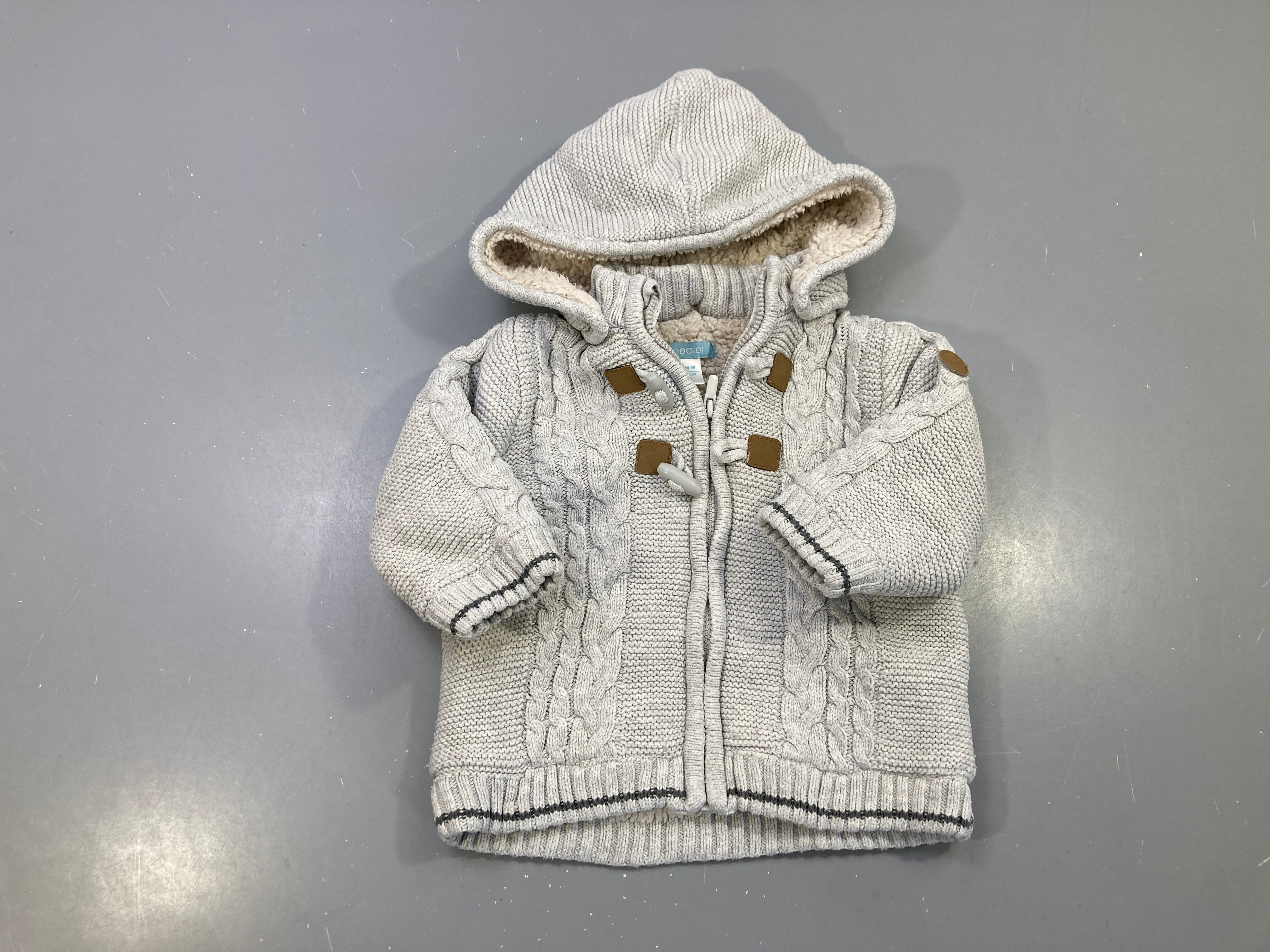 Gilet maille torsadée gris clair zippé, capuche doublée sherpa, attaches duffle-coat