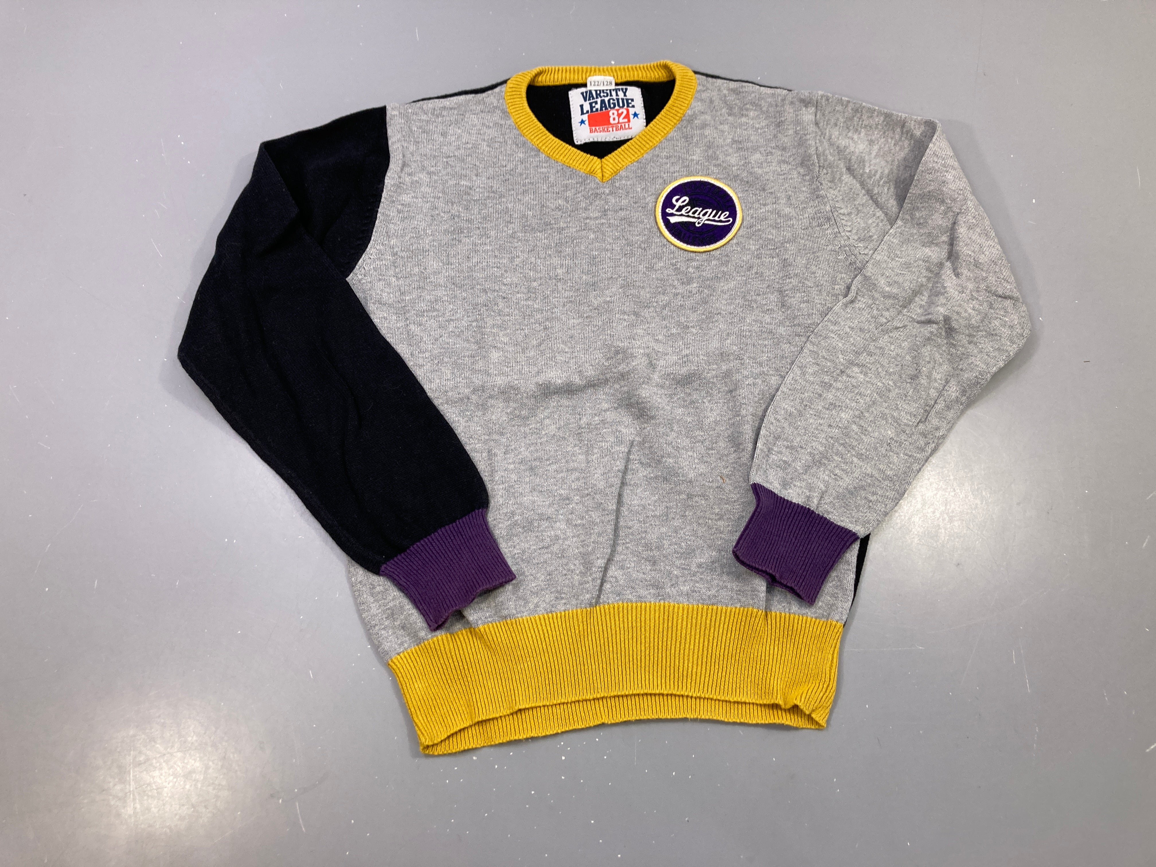 Pull col V gris, manche noire, bords moutarde et violets, écusson League, Varsity League