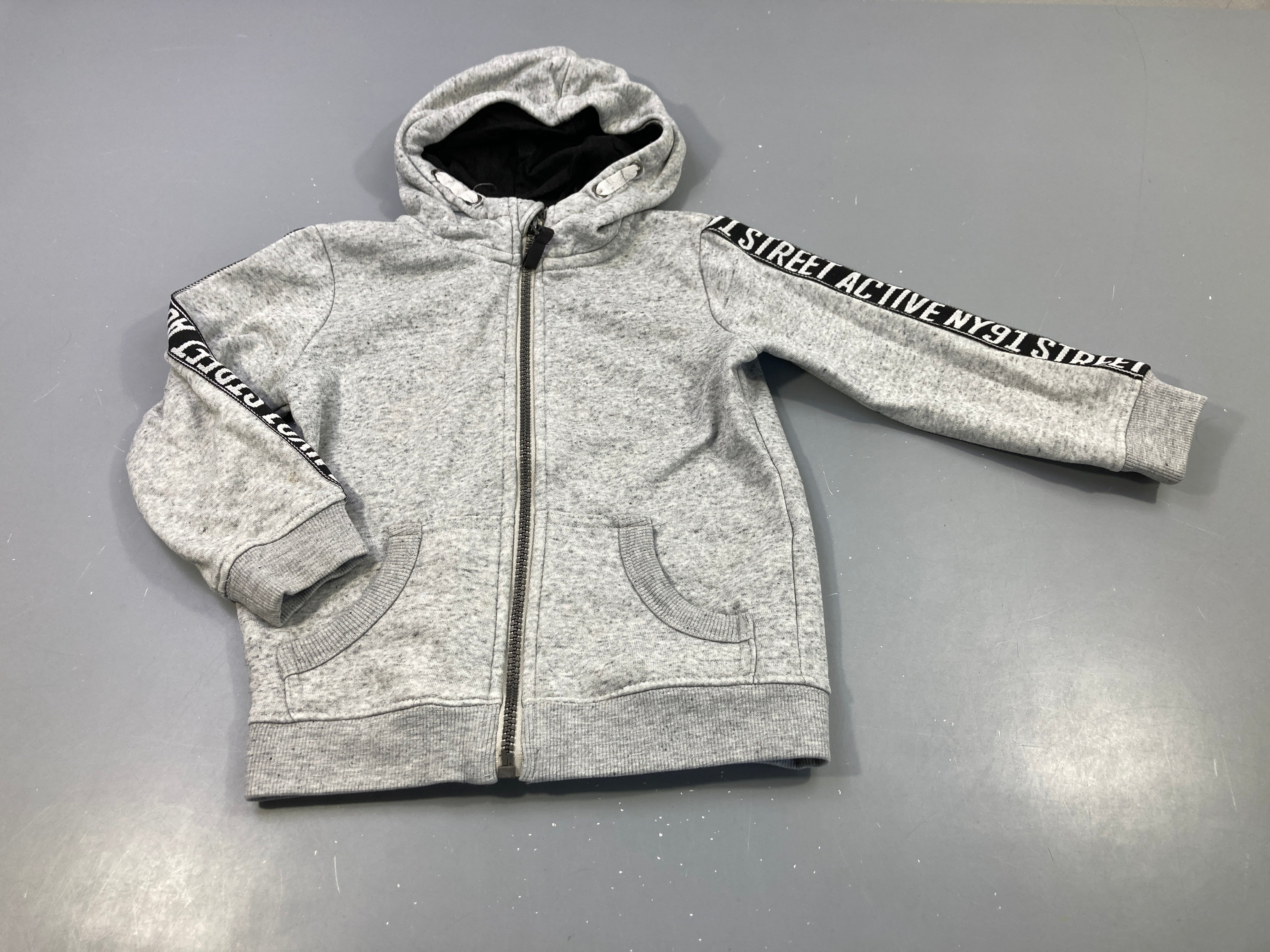 Sweat zippé à capuche gris clair chiné, très légèrement bouloché . Tache manche droite